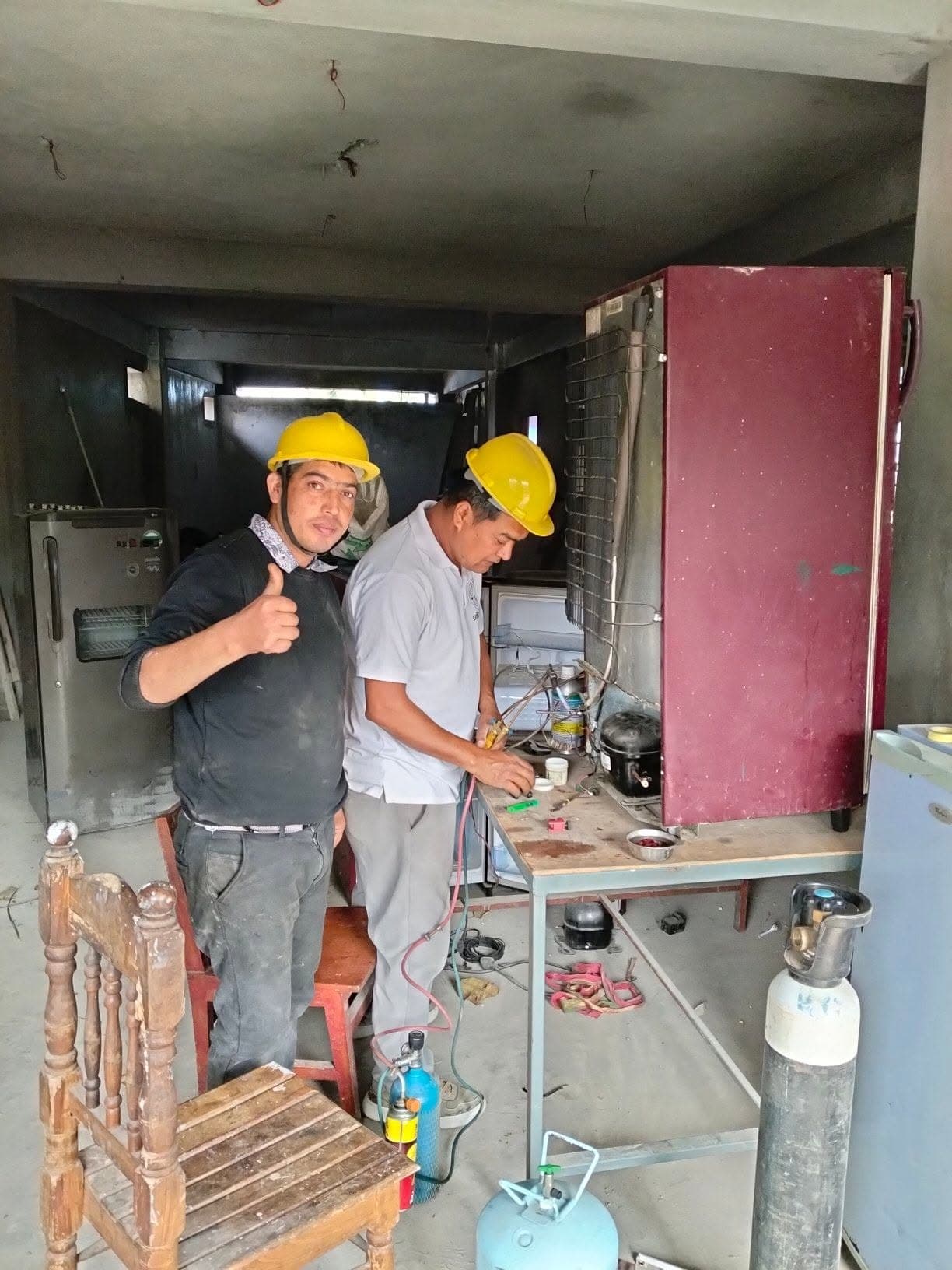 Technicians repairing a refrigerator compressor